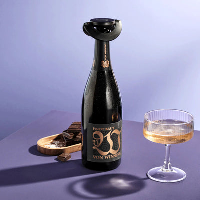Bottle of Pinot Brut with a wine glass on a purple background
