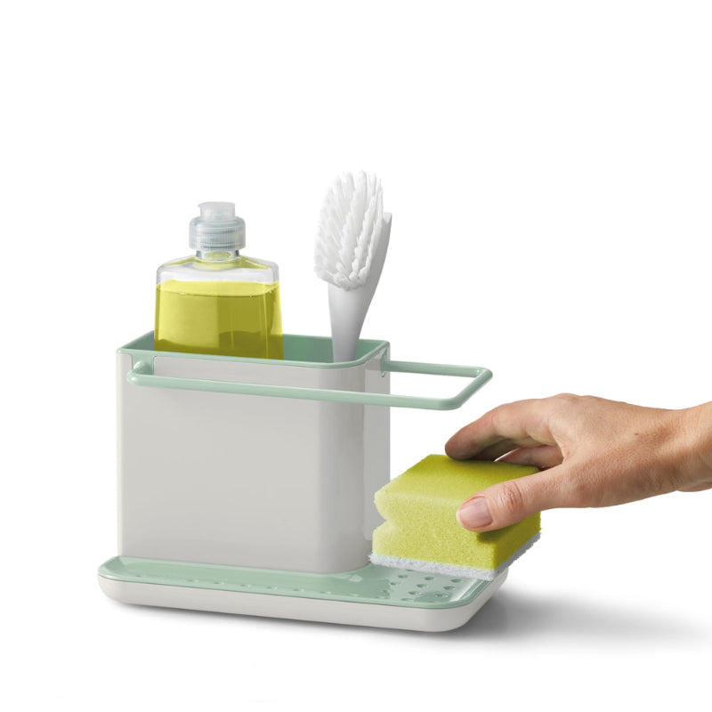 Dishwashing station with sponge, brush, and soap bottle on a white background
