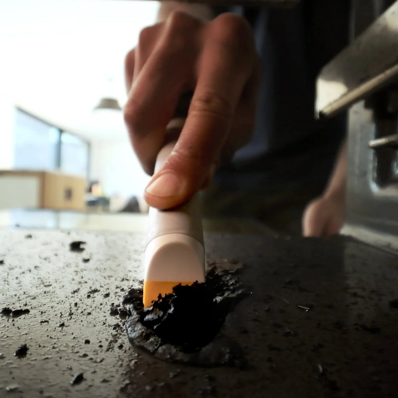 Person cleaning a stovetop with a brush