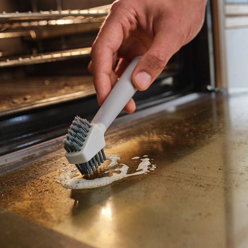 Person cleaning an oven with a brush