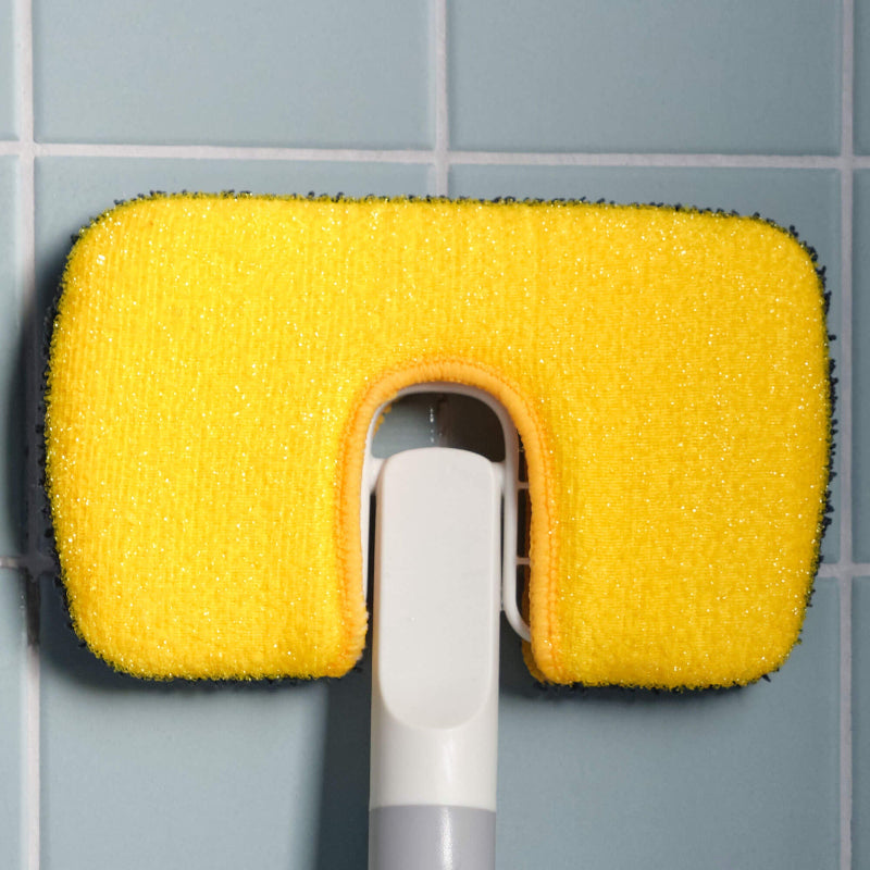 Yellow sponge scrubber on a gray tiled wall