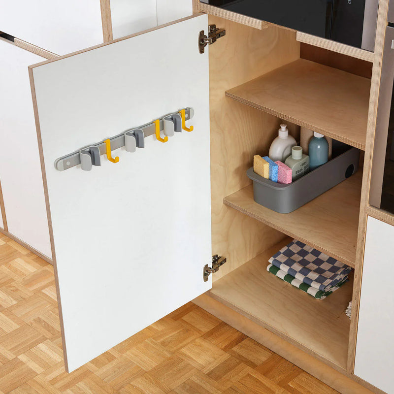 Open kitchen cabinet with hooks and storage items on a wooden floor.