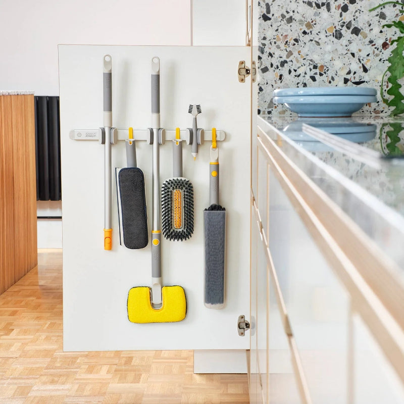 Cleaning tools hanging on a magnetic strip in a kitchen.