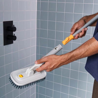 Person cleaning a tiled wall with a scrubber tool