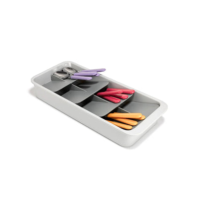White tray with compartments containing colourful cutlery on a white background