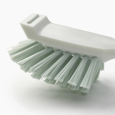 White brush with green bristles on a white background