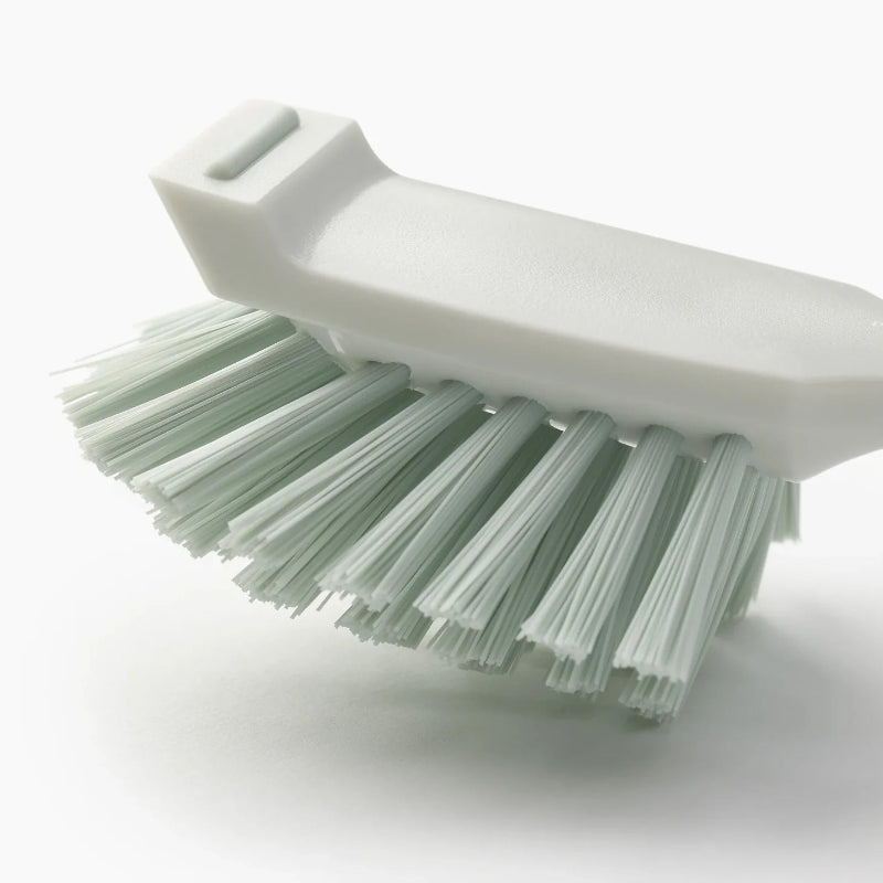 White brush with green bristles on a white background