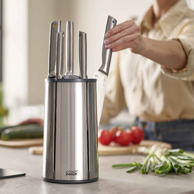 Person using a knife sharpener with a kitchen setting in the background
