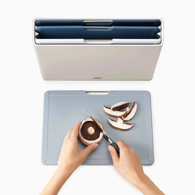 Person cutting mushrooms on a cutting board with a knife, next to a blue and white container.