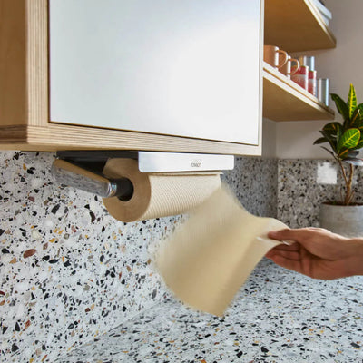 Person taking a roll of paper towels from a holder on a kitchen counter.