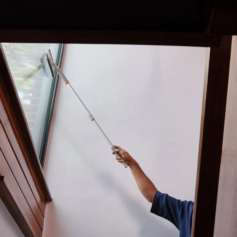 Person cleaning a window with a squeegee inside a building.