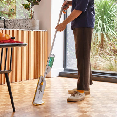 Person cleaning a wooden floor with a mop in a modern kitchen.