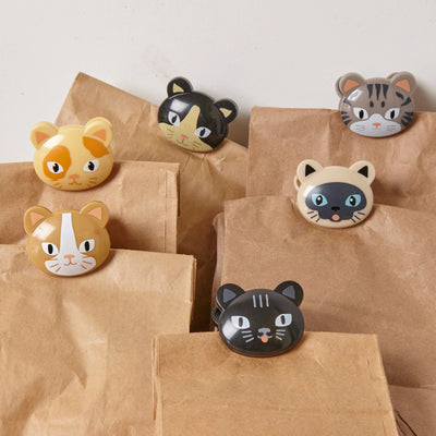 Cat-shaped clips on brown paper bags against a light background