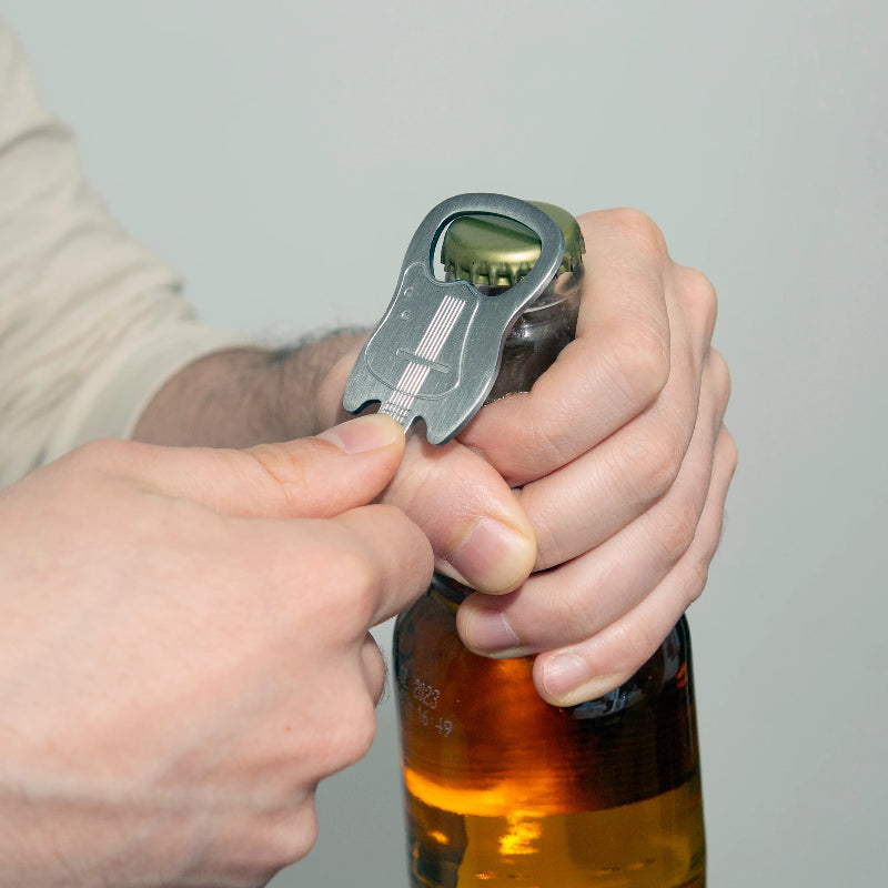 Person using a bottle opener on a bottle against a neutral background