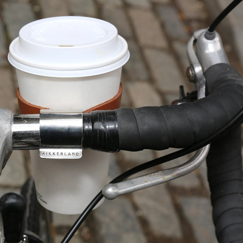 Coffee cup holder with a white coffee cup attached to bicycle handlebars.