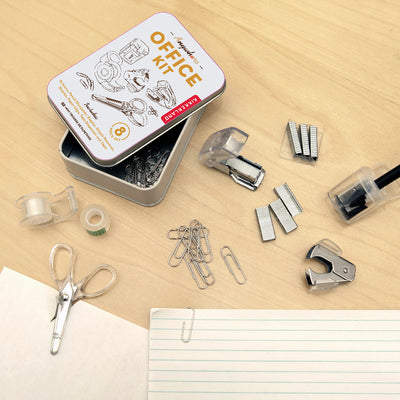 Collection of office supplies including a tin labeled 'Office Kit' on a wooden surface.