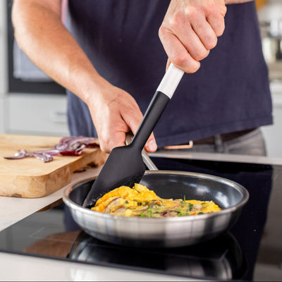 Person cooking eggs in a pan with a spatula in a kitchen setting