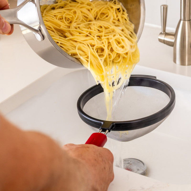 Person pouring pasta from a colander into a sink