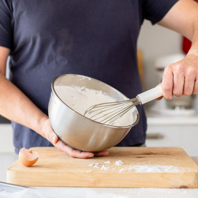 Person whisking ingredients in a bowl on a kitchen counter