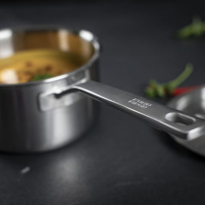 Stainless steel measuring cup on a dark surface with blurred background