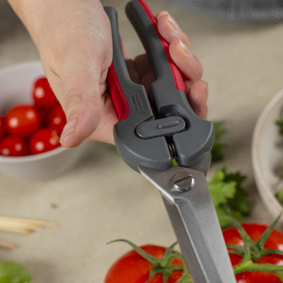 Hand using kitchen shears with vegetables on a table
