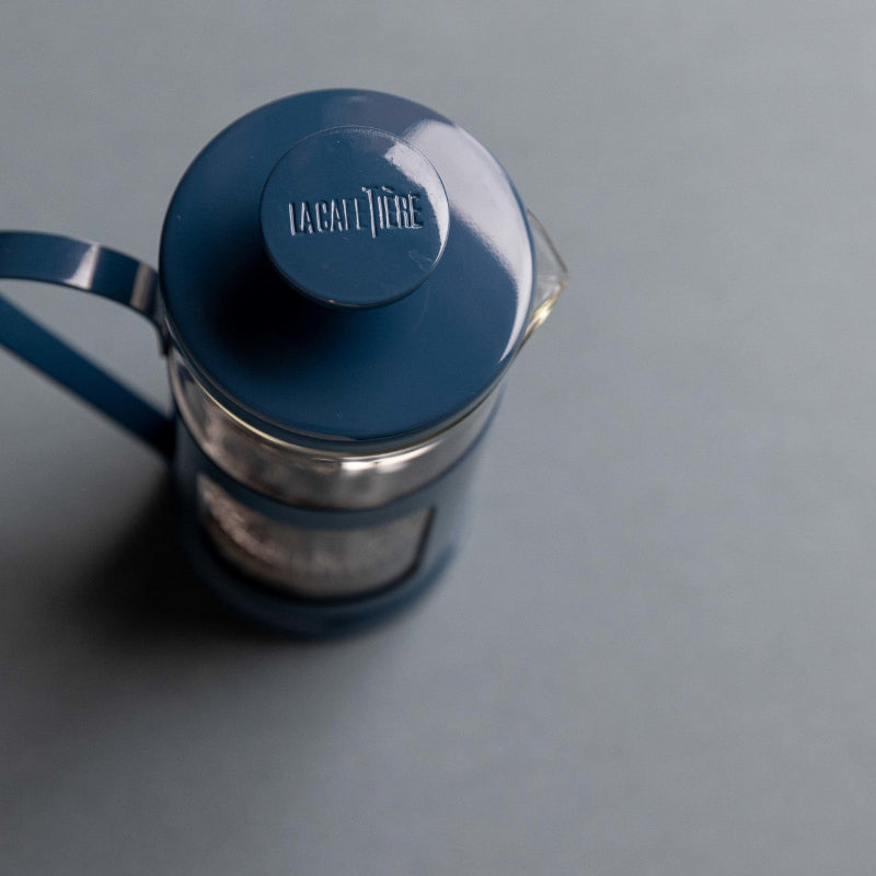 Blue French press coffee maker on a gray background