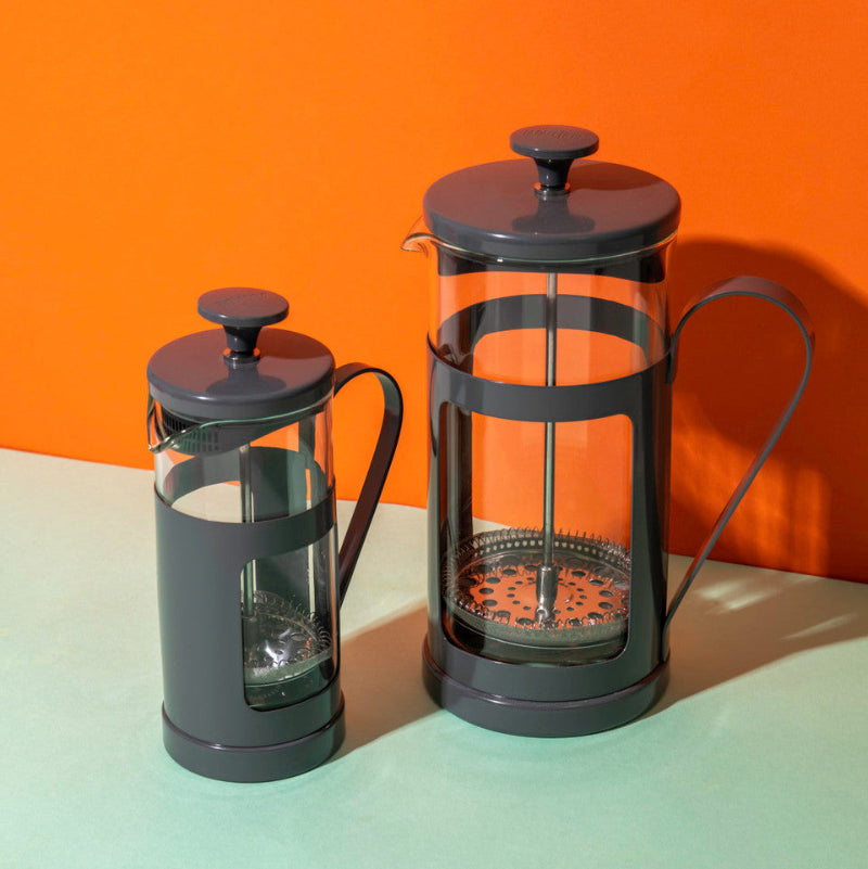 Two French presses on a gradient background with an orange to green color transition.