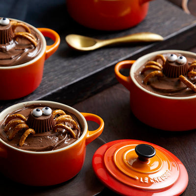 Red ceramic pots with chocolate dessert on a dark surface