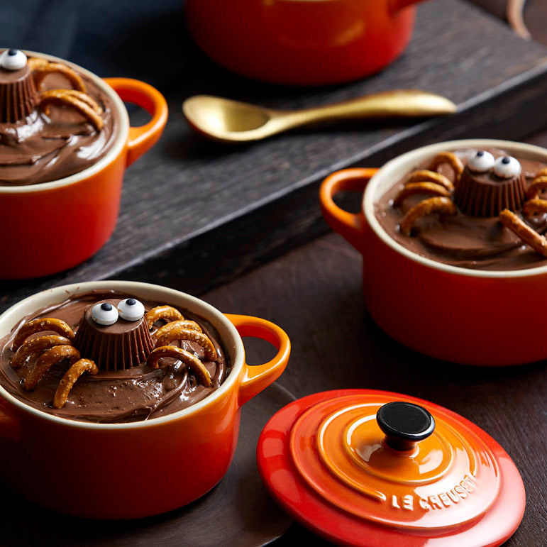 Red ceramic pots with chocolate dessert on a dark surface