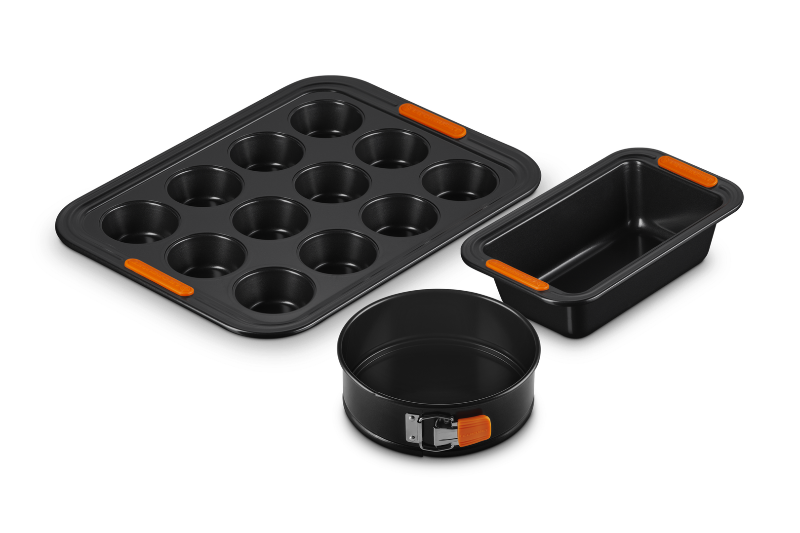 Set of black baking pans with orange accents on a white background