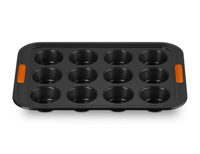 Black muffin tin with orange handles on a white background