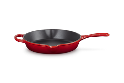Red frying pan with a black interior on a white background