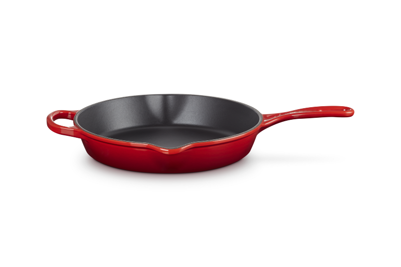 Red frying pan with a black interior on a white background