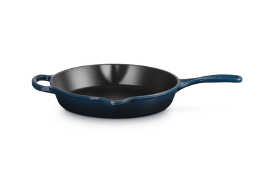 Black cast iron skillet with blue handle on a white background