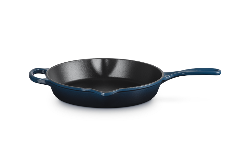 Black cast iron skillet with blue handle on a white background