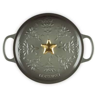 Green cast iron skillet with star design and 'Le Creuset' branding on a white background