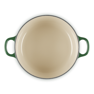 Round beige enamel cookware with green handles on a white background