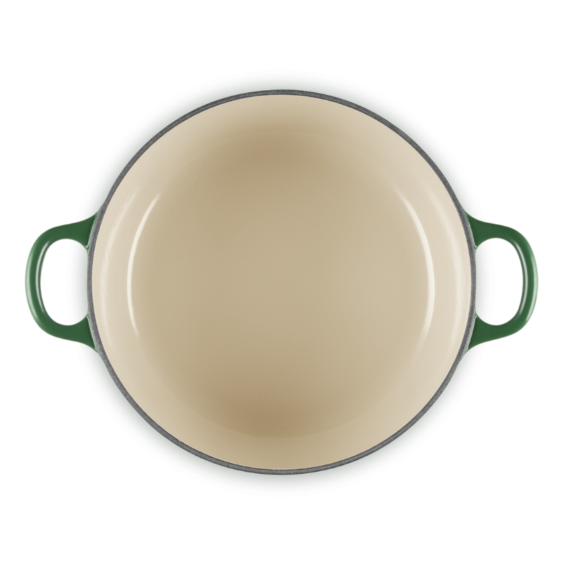 Round beige enamel cookware with green handles on a white background