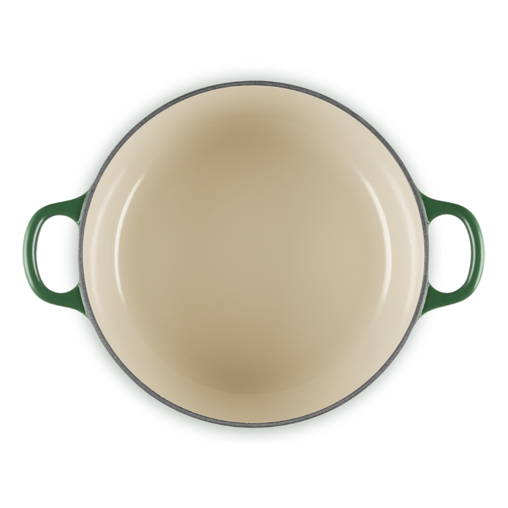 Round beige enamel cookware with green handles on a white background