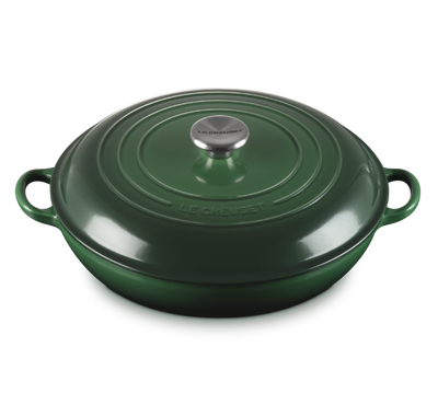 Green cast iron cookware with a lid on a white background