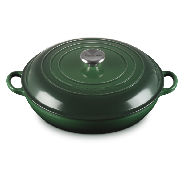 Green cast iron cookware with a lid on a white background