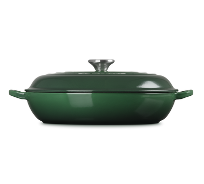 Green enameled cast iron casserole dish with lid on a white background