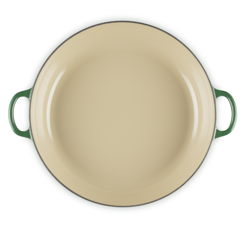 Beige enamel pan with green handles on a white background