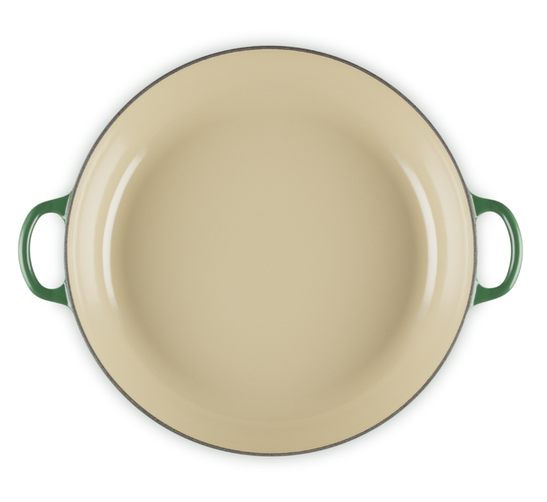 Beige enamel pan with green handles on a white background