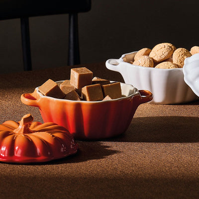 Decorative bowls with brown cubes and white pumpkins on a brown surface