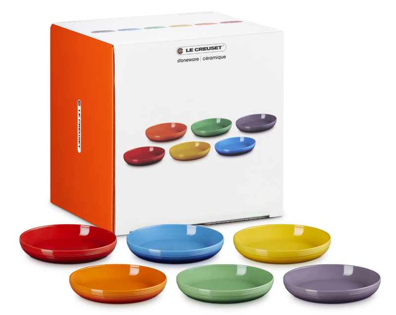 Set of colorful ceramic bowls in front of Le Creuset packaging.