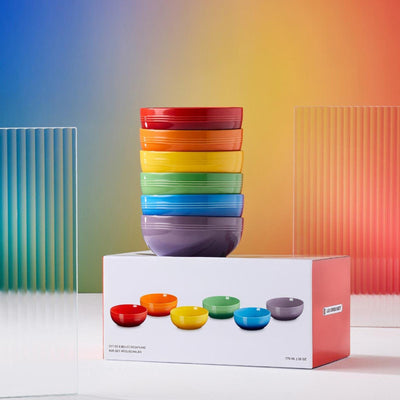 Stack of colorful bowls with a matching set on a box against a gradient background