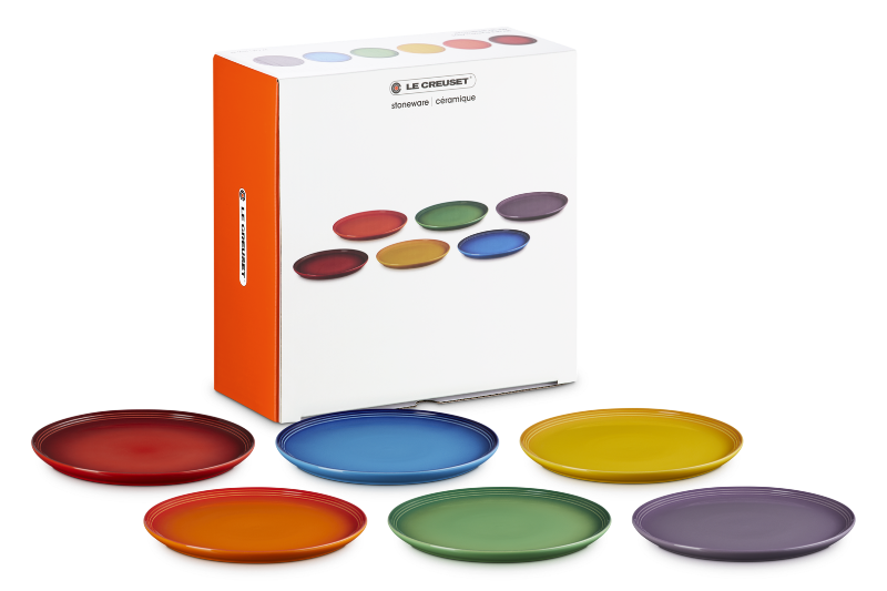 Set of colorful plates with Le Creuset packaging on a white background