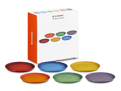 Set of colorful plates with a Le Creuset box on a white background
