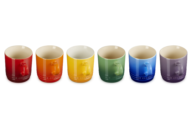 Set of six colorful mugs arranged in a row on a white background